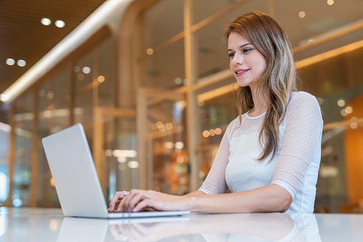 Close up mid shot of multiracial businesswoman using laptop from a workspace with cafe working out of home, from a workspace shared office cafe.