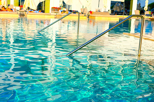 Horizontal color rear image of pretty woman relaxing in infinity pool, looking at sea view and enjoying vacations.