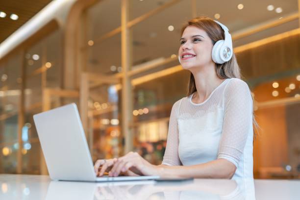 istock Casual businesswoman using laptop and headphone doing e-learning and video conferencing from a workspace with cafe 1488165253