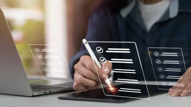 Photo of Concept of a company performance checklist, with a businesswoman completing a digital form checklist while using a laptop and tablet.