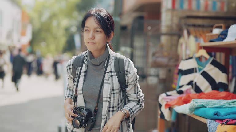 Asian young woman is taking a look at a second-hand hat in flea market.