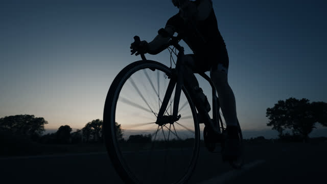 Low-angle view of Silhouette of Male Athlete Cycling Road Bike at Night