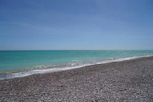 waves on mediterranean sea with pebble beach and green water