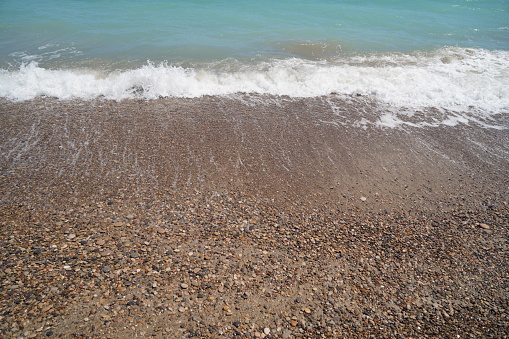 waves on mediterranean sea with pebble beach and green water