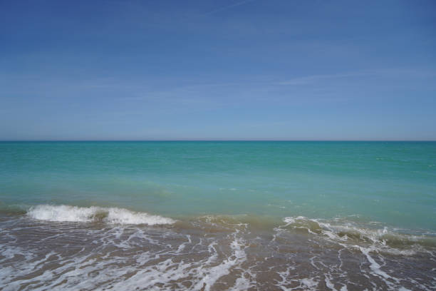 waves on mediterranean sea with pebble beach and green water