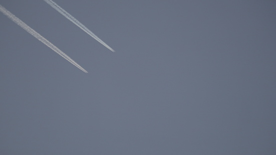 Two airplanes fly together in the blue sky. Two aircrafts with two parallel trails.