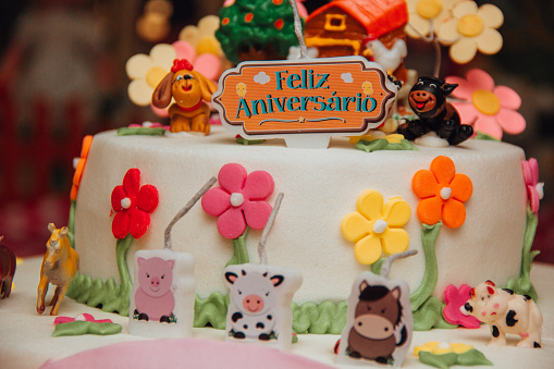 A colorful birthday cake decorated with fondant toppings in forms of animals and flowers