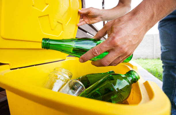 istock Man throwing the glass bottle into one of three dustbins for sorting trash 1488186497