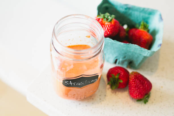 Jar of homemade strawberry vinaigrette with fresh strawberries on the side from above