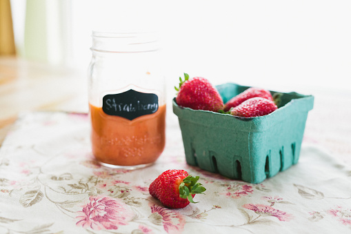 Jar of strawberry vinaigrette and strawberries on a table
