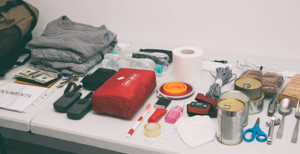 istock Emergency backpack equipment organized on the table. Documents, water,food, first aid kit and another items needed to survive. 1488189279