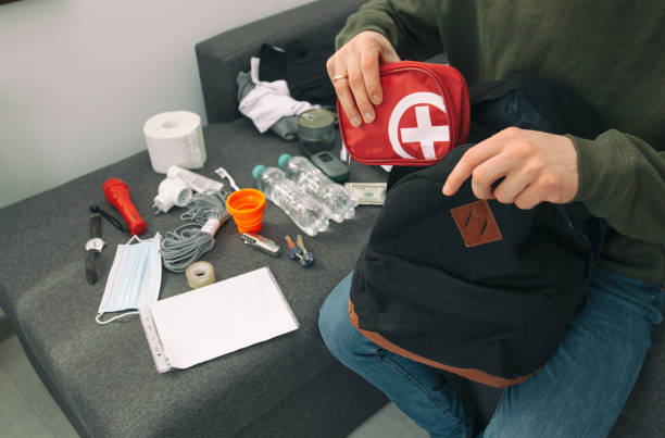 Young man packing the bag with documents, water,food, first aid kit and other items needed to survive stock photo