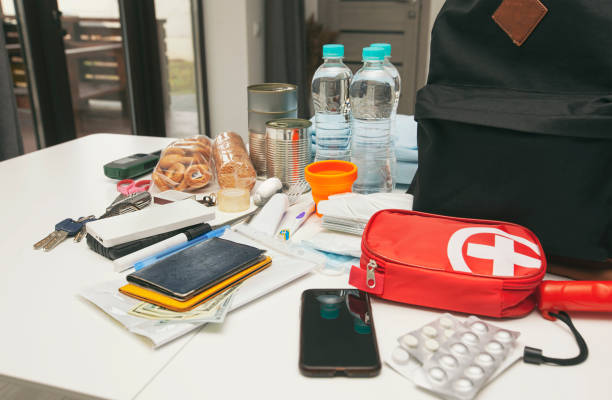 istock Emergency backpack equipment organized on the table. Documents, water,food, first aid kit and another items needed to survive. 1488189429