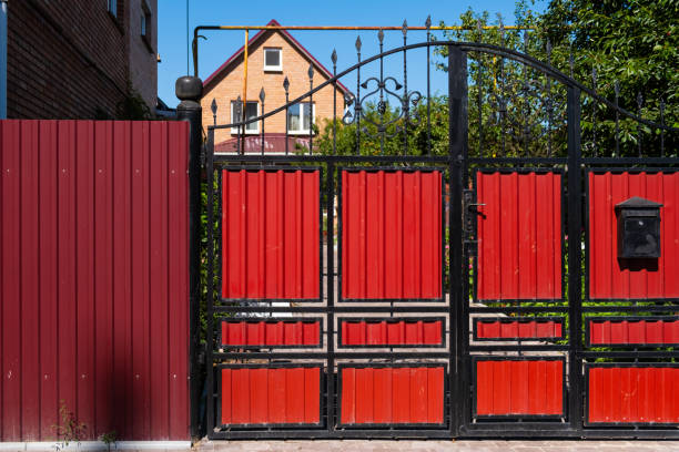 современные красные декоративные ворота с элементами из кованого железа возле жилого дома. - security bar стоковые фото и изображения