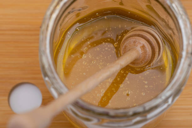 istock Bee honey in glass jar with wooden spoon 1488214927