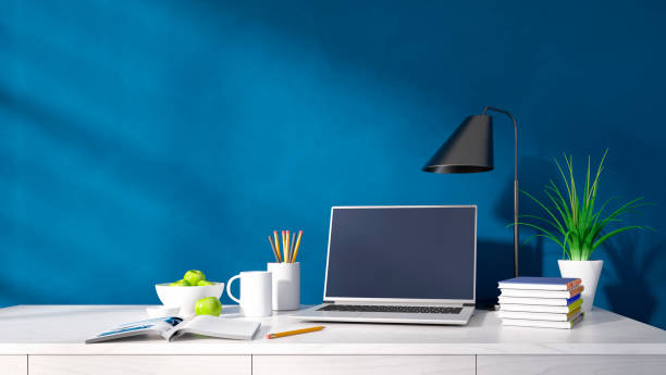 Modern home office desk against blue wall stock photo