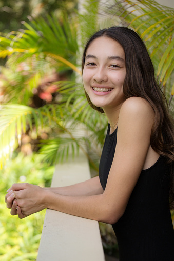 A young Hawaiian teen adolescent girl in her home, looking at camera, smiling.