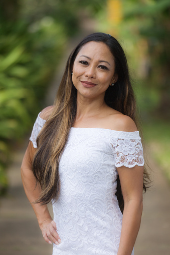 A Hawaiian woman in formal white dress, Smiling posing and looking at camera
