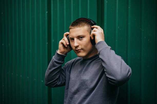 Young teenage boy with wireless headphones listening to music from his mobile phone