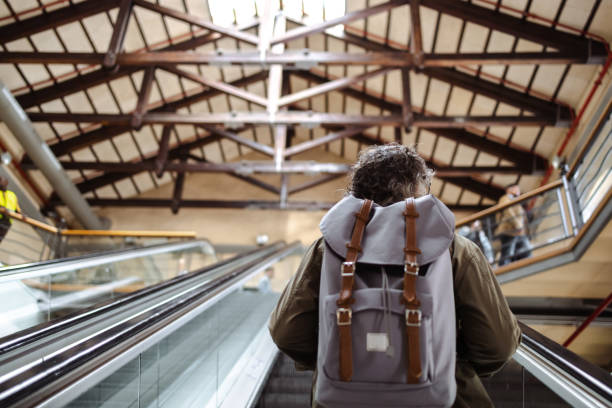 Rear view of mature tourist woth backpack on the escalator