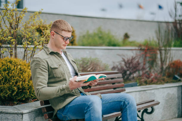 istock Young Man Reading Book Outdoors 1488224247