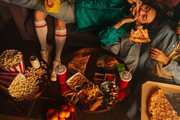 A relaxed retro group of friends are at home, eating pizza and relaxing on the sofa.
