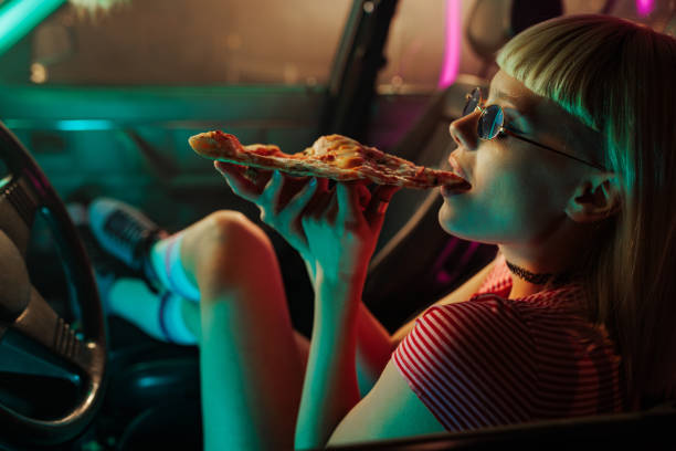 istock Girl eating pizza in car. 1488224928