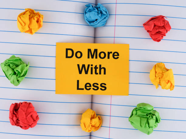 istock A yellow paper note with the phrase Do More With Less on notebook sheet with some colorful crumpled paper balls around it 1488225028