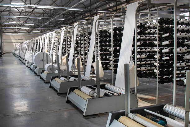 Many large coils wind ready-made propylene sleeves from woven threads for the manufacture of industrial bags. PP bag production line stock photo