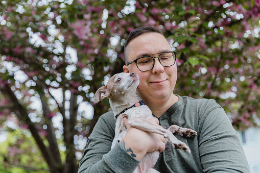 Portrait of a mid adult man outdoors in a residential neighborhood who is on the autism spectrum. He has ADHD as well as autism and enjoys life even with some of the challenges presented with his diagnosis. He is with his pet dog who is comforting to him.