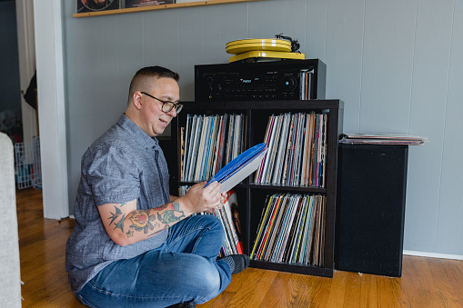 An Autistic man enjoys listening to vinyl records at home with his stereo and turn table. It is his hobby and listening to music is comforting to him and helps him with sensory overload which stems from autism.