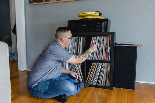 An Autistic man enjoys listening to vinyl records at home with his stereo and turn table. It is his hobby and listening to music is comforting to him and helps him with sensory overload which stems from autism.