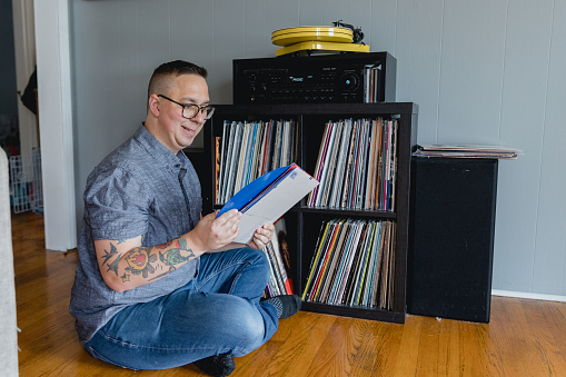An Autistic man enjoys listening to vinyl records at home with his stereo and turn table. It is his hobby and listening to music is comforting to him and helps him with sensory overload which stems from autism.