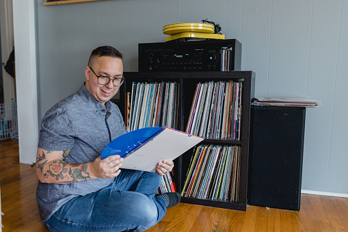 An Autistic man enjoys listening to vinyl records at home with his stereo and turn table. It is his hobby and listening to music is comforting to him and helps him with sensory overload which stems from autism.