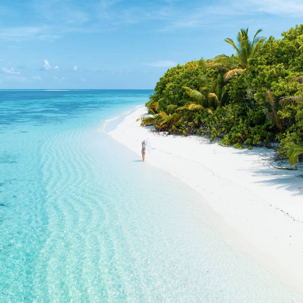 Aerial drone view of a woman walking on desert island in Maldives stock photo