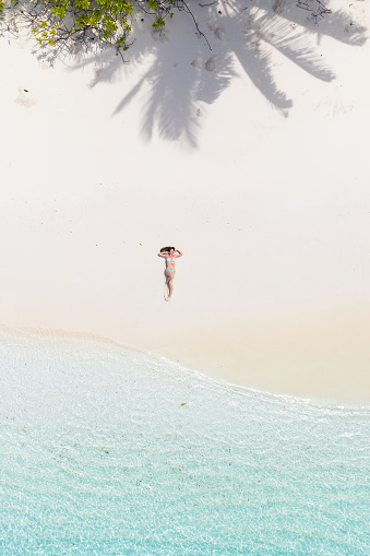Aerial drone view of a woman lying down on a sandy beach