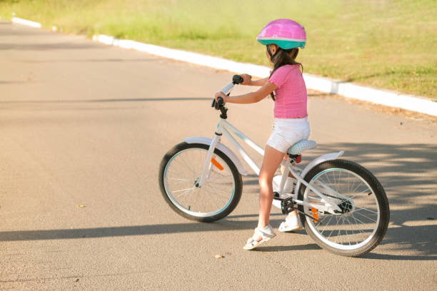 istock A girl in a protective pink helmet is learning to ride a bicycle. 1488228251