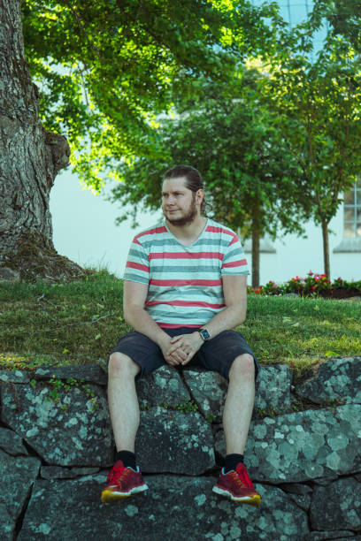 istock a man sitting on a stone wall in a park 1488228274