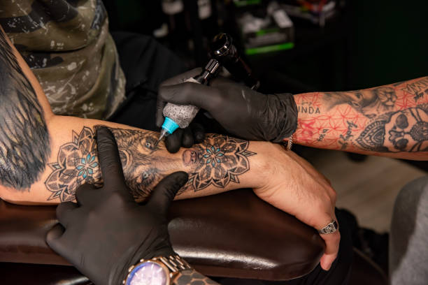 istock Professional tattooer doing tattoo on hand using tattoo machine in studio 1488229604