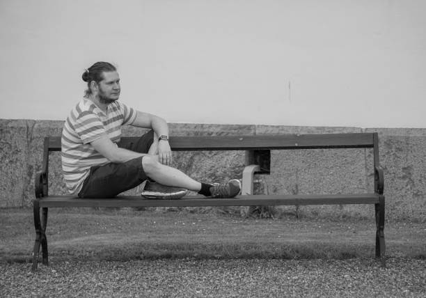 istock a man sitting on a bench in front of a building 1488229630