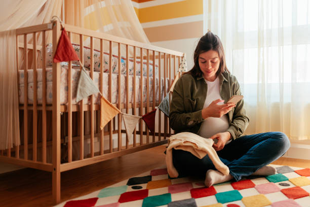 Smiling pregnant woman using cellphone at home.