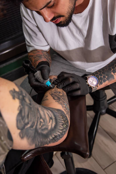 istock Professional tattooer doing tattoo on hand using tattoo machine in studio 1488230567