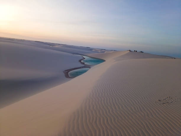 Photo taken in Lençois Maranhenses, Brazil. Photo taken in Lençois Maranhenses, Brazil, dunes reddened by the light of the sunset, lakes with blue water and the reddish sky at dusk. brazil desert maranhao state national park stock pictures, royalty-free photos & images