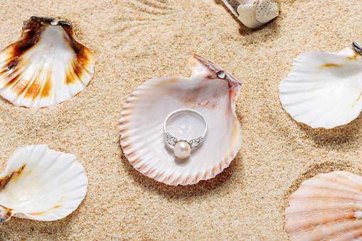 Silver ring with pearls on a sandy beach close-up