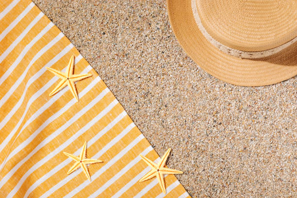 istock Straw hat and beach towel on the beach sand 1488238538