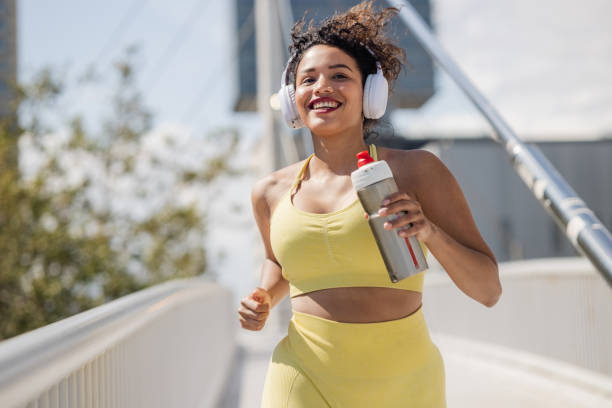 a woman in sportswear jogging outdoors on a sunny day - self improvement audio imagens e fotografias de stock