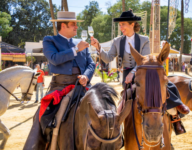 A couple of riders in Feria de Jerez with their horses. toasting with a glass of sherry A couple of riders in Feria de Jerez with their horses. toasting with a glass of sherry jerez de la frontera stock pictures, royalty-free photos & images