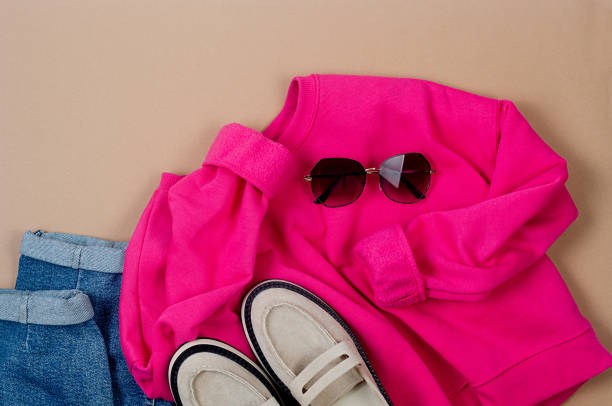 istock Pink sweatshirt, Blue jeans, beige suede loafers and sunglasses on white background. 1488242569