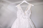A beautiful wedding dress hangs on a hanger in a white room,. Preparation for the ceremony