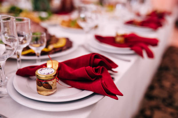 istock Restaurant Serving Banquet Catering, Wedding Dinner. Lay the table with white plates and red napkins with a small jar of honey and nuts. 1488244608